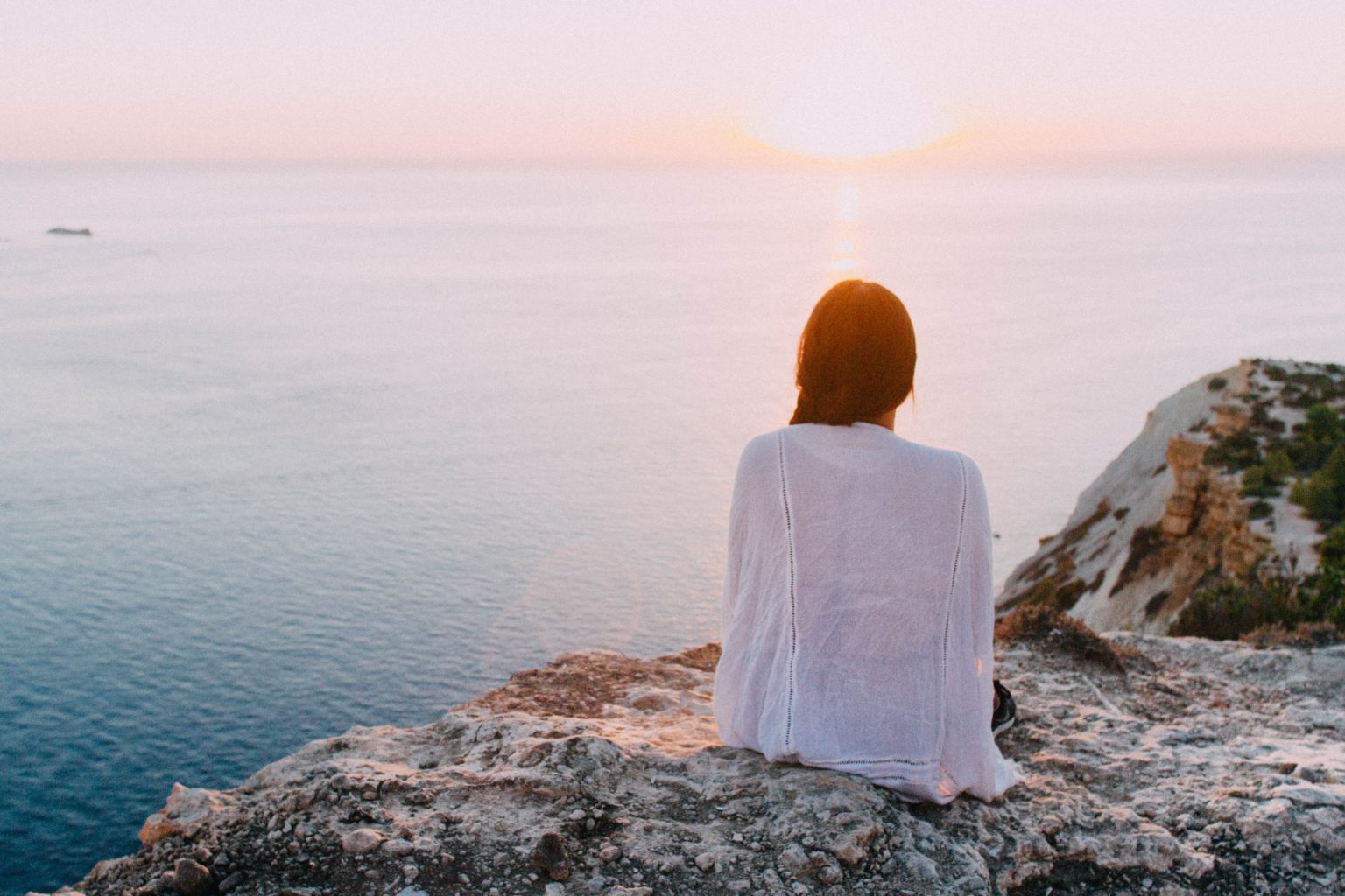 a man sitting on a rock looking at the sea