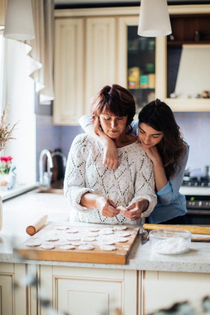 a person and a young girl making dough in a kitchen