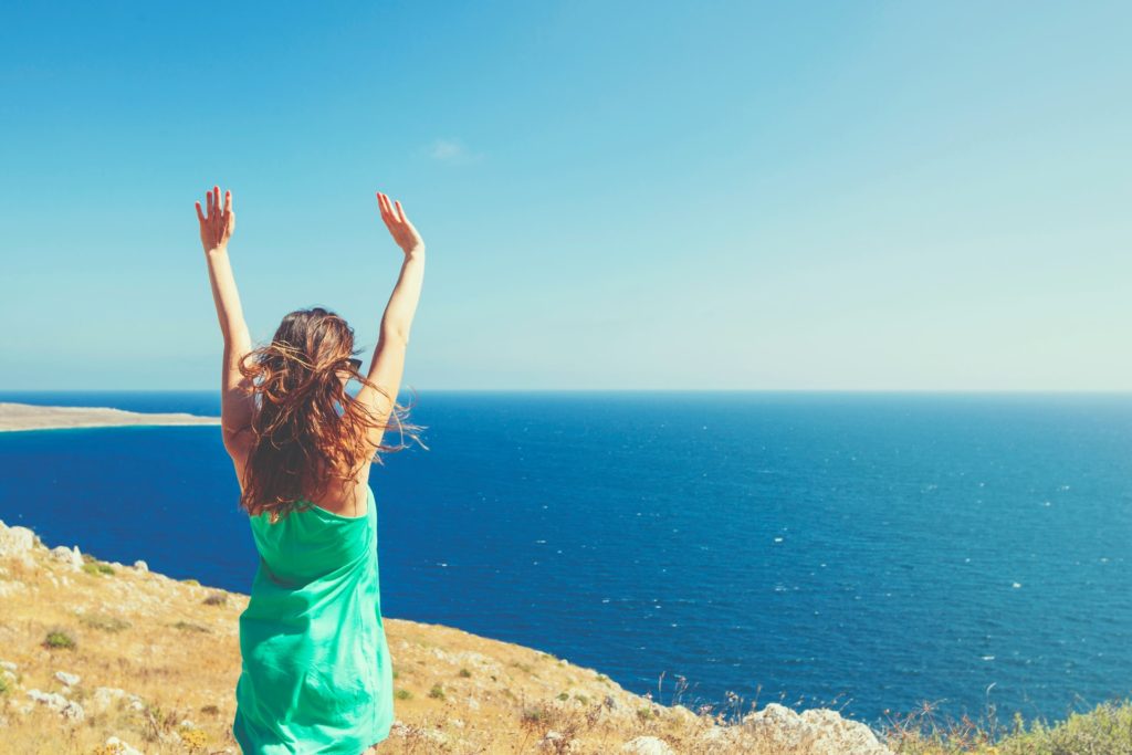 a man standing on a cliff with his arms raised