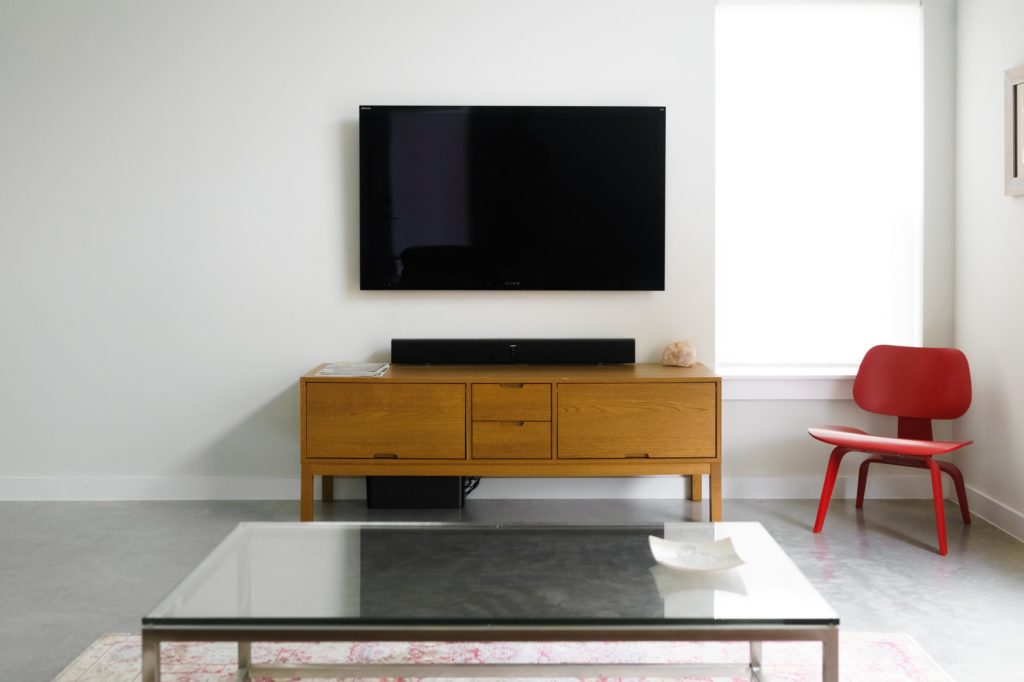 a tv on a stand in a room with a table and chairs